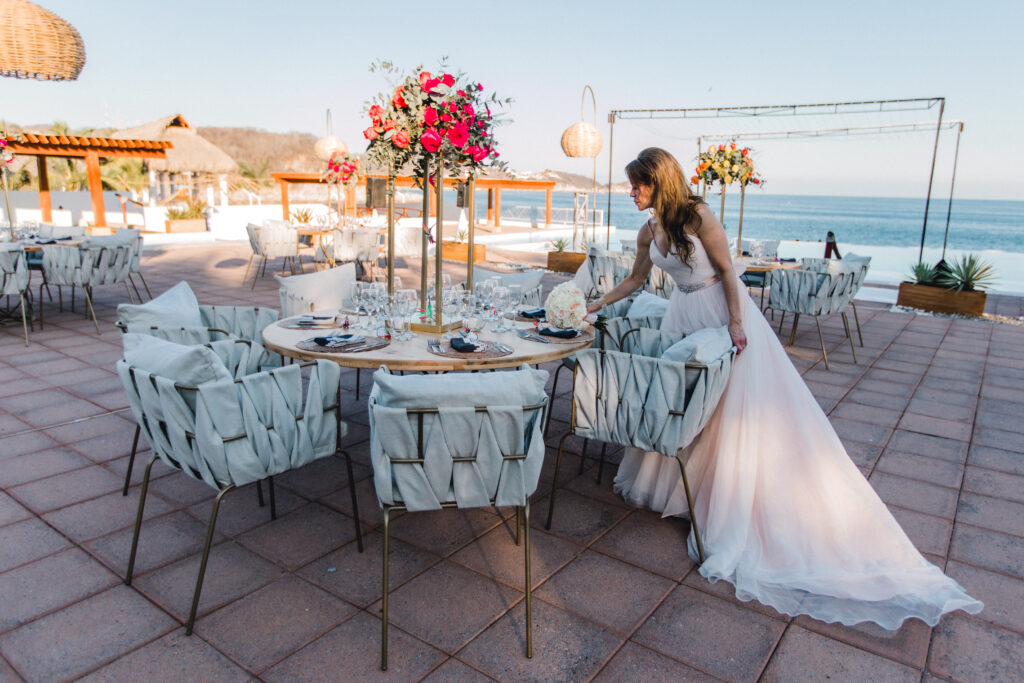 Novia disfrutando del centro de mesa y los detalles en una boda frente al mar en Sea Soul, Huatulco